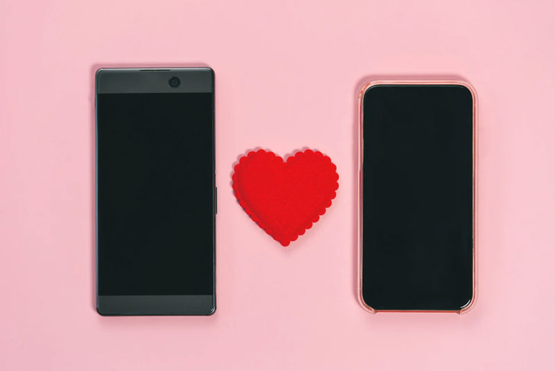 Image of two cell phones on a pink background with a red heart between the phones