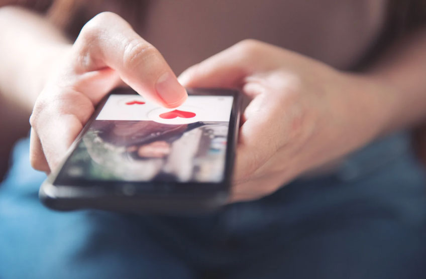 Image of a woman holding a mobile phone and browsing a dating app